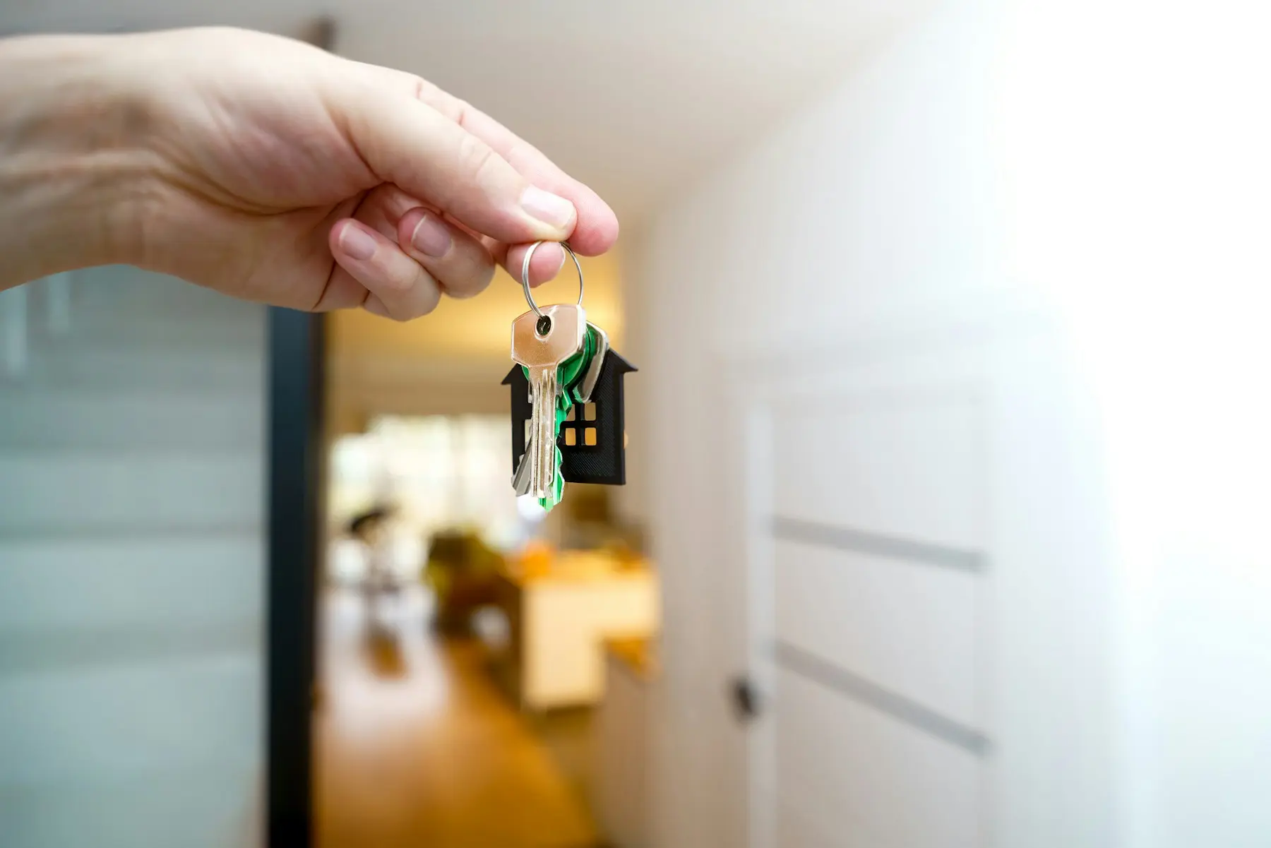 Hand holding the keys to a new home in an open doorway