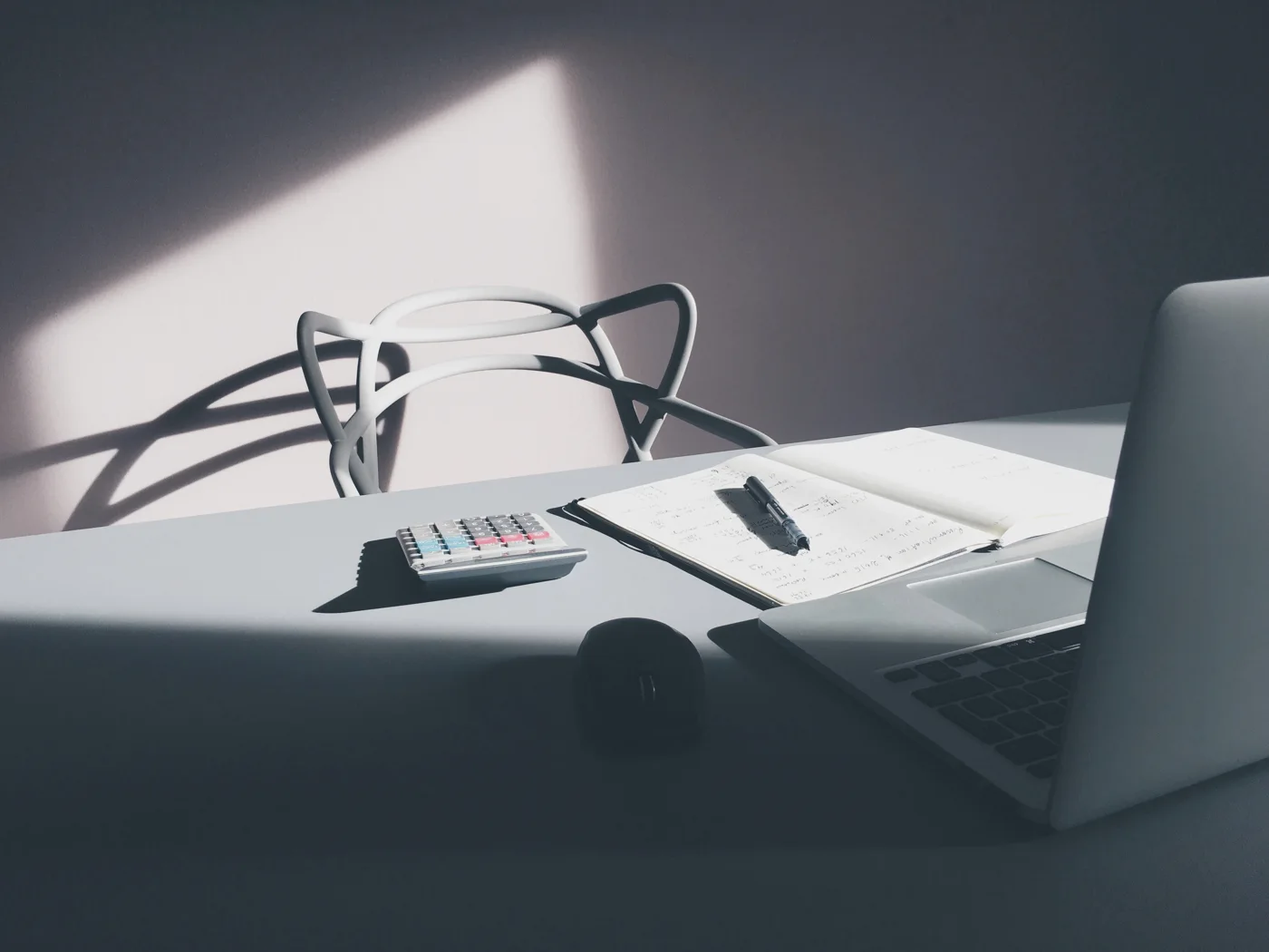 Calculator, notebook and laptop on a sunlit desk
