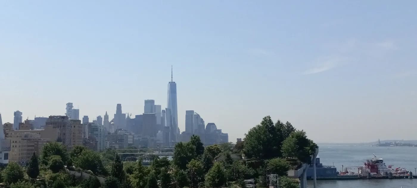Lower Manhattan skyline and One World Trade Center viewed across a waterfront park