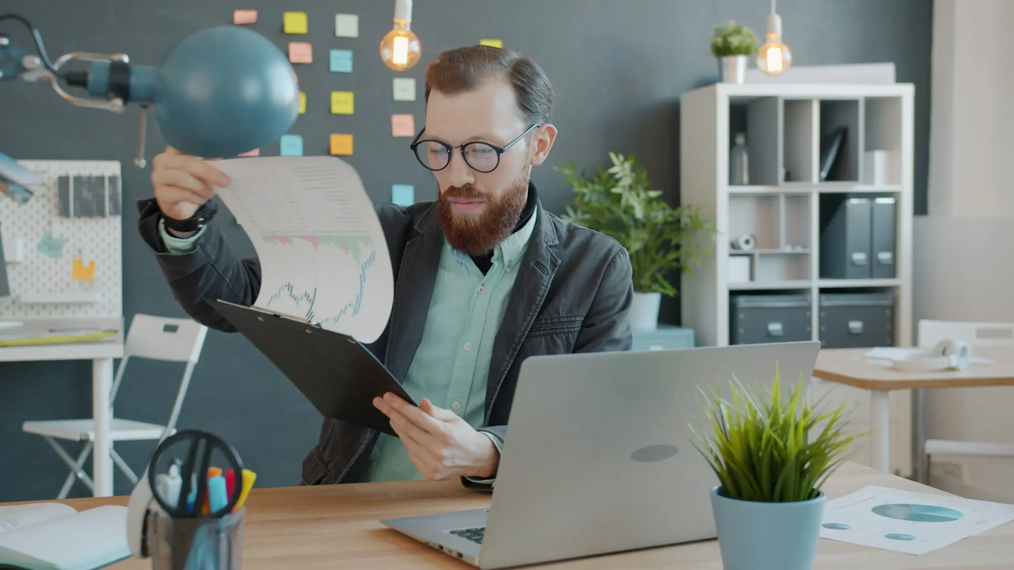 Professional reviewing document pages and their order beside a laptop
